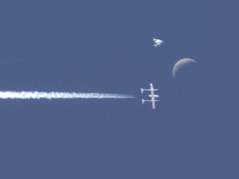 SpaceShipOne released from the White Knight mothership beneath a crescent moon. (Credit: Scaled Composites/SpaceDaily)